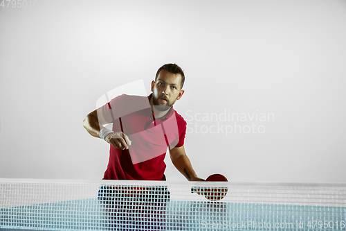 Image of Young man playing table tennis on white studio background