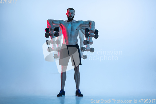 Image of Young caucasian bodybuilder training over blue background