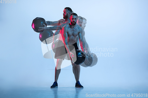 Image of Young caucasian bodybuilder training over blue background