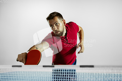 Image of Young man playing table tennis on white studio background