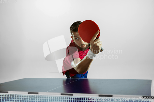Image of Young man playing table tennis on white studio background