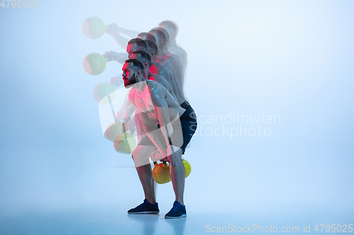 Image of Young caucasian bodybuilder training over blue background