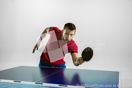 Image of Young man playing table tennis on white studio background