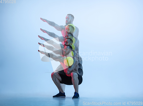 Image of Young caucasian bodybuilder training over blue background