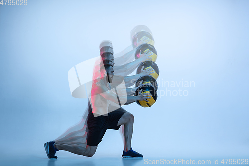 Image of Young caucasian bodybuilder training over blue background