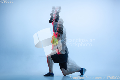 Image of Young caucasian bodybuilder training over blue background