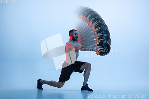 Image of Young caucasian bodybuilder training over blue background