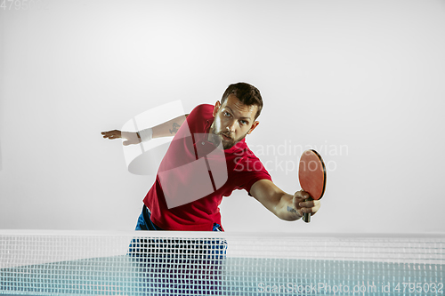 Image of Young man playing table tennis on white studio background