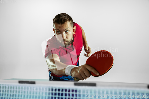 Image of Young man playing table tennis on white studio background