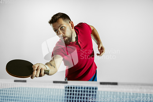 Image of Young man playing table tennis on white studio background