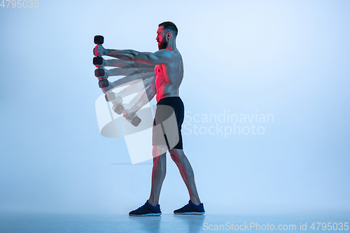 Image of Young caucasian bodybuilder training over blue background