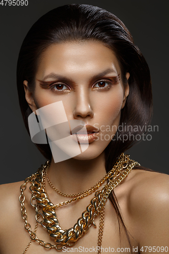 Image of beautiful girl with many golden and bronze chains