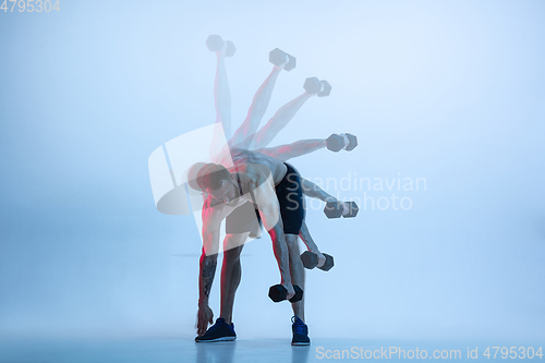 Image of Young caucasian bodybuilder training over blue background