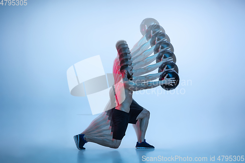 Image of Young caucasian bodybuilder training over blue background