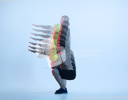 Image of Young caucasian bodybuilder training over blue background