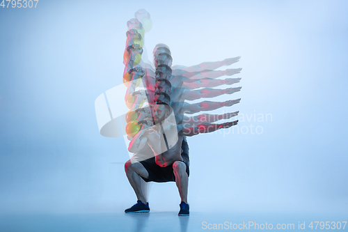 Image of Young caucasian bodybuilder training over blue background