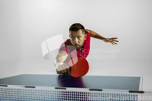 Image of Young man playing table tennis on white studio background