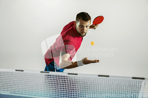 Image of Young man playing table tennis on white studio background