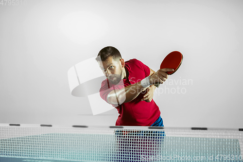 Image of Young man playing table tennis on white studio background