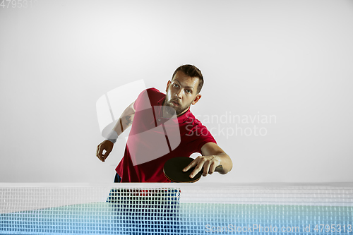 Image of Young man playing table tennis on white studio background