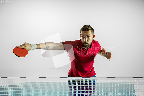 Image of Young man playing table tennis on white studio background