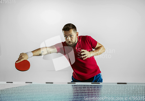 Image of Young man playing table tennis on white studio background