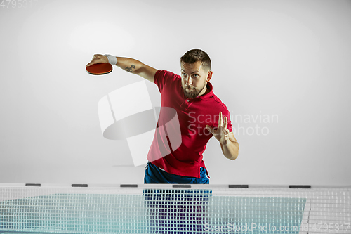 Image of Young man playing table tennis on white studio background