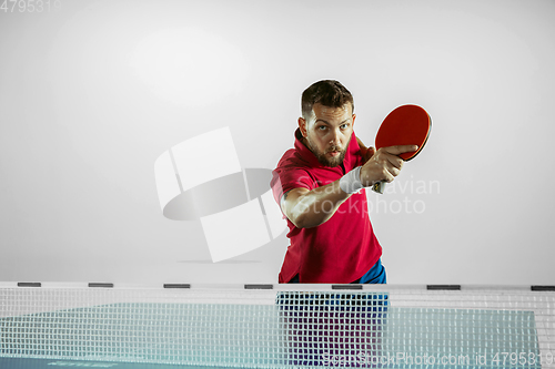 Image of Young man playing table tennis on white studio background