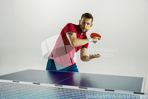 Image of Young man playing table tennis on white studio background