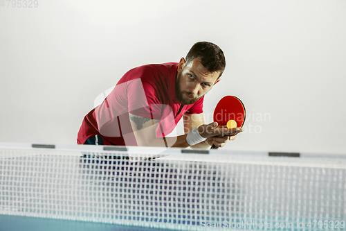 Image of Young man playing table tennis on white studio background