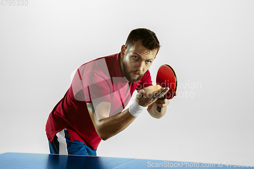 Image of Young man playing table tennis on white studio background