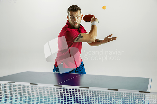 Image of Young man playing table tennis on white studio background