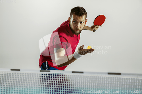 Image of Young man playing table tennis on white studio background