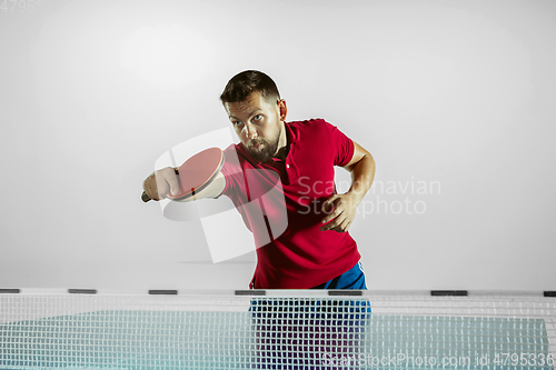 Image of Young man playing table tennis on white studio background