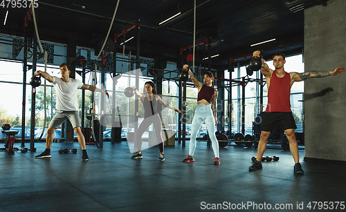 Image of A group of muscular athletes doing workout at the gym