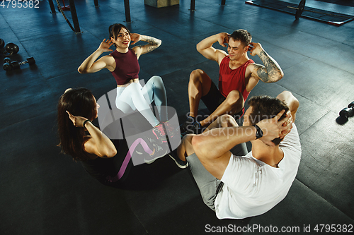 Image of A group of muscular athletes doing workout at the gym