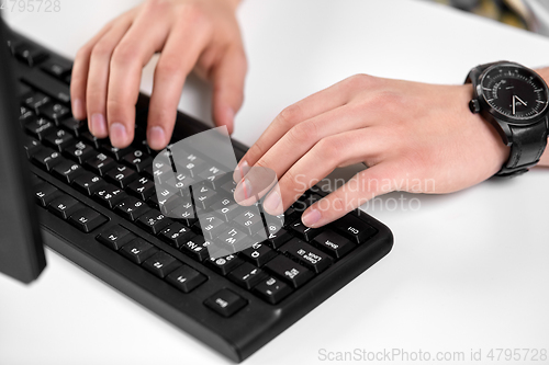 Image of male hands typing on computer keyboard on table