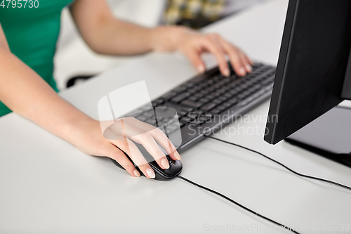 Image of female hand with computer mouse on table