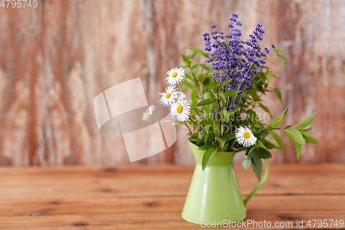 Image of bunch of herbs and flowers in green jug on table