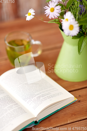 Image of herbal tea, book and flowers in jug on table