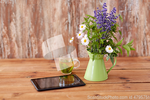 Image of tablet computer, herbal tea and flowers in jug