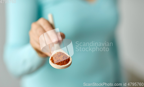 Image of close up of woman with turmeric on wooden spoon