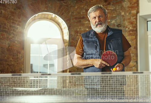 Image of Senior man playing table tennis in workplace, having fun