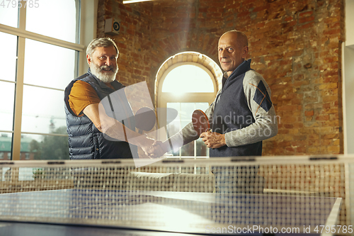 Image of Senior men playing table tennis in workplace, having fun