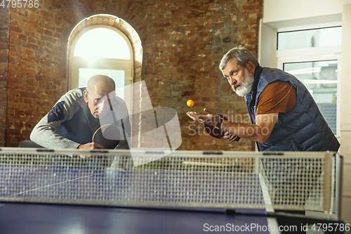 Image of Senior men playing table tennis in workplace, having fun