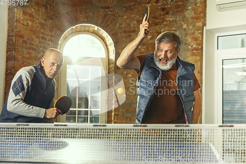 Image of Senior men playing table tennis in workplace, having fun