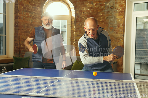 Image of Senior men playing table tennis in workplace, having fun