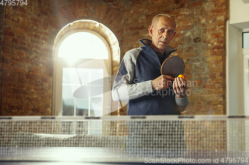 Image of Senior man playing table tennis in workplace, having fun