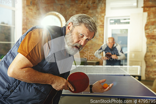 Image of Senior men playing table tennis in workplace, having fun