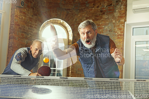 Image of Senior men playing table tennis in workplace, having fun